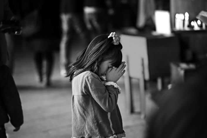Foto Reportage in bianco e nero realizzate in Giappone, Usi e costumi di un popolo, qui in foto una bambina china in preghiera